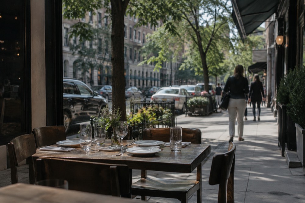 A small neighborhood restaurant with awnings and sidewalk tables on a side street