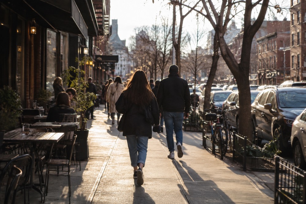 People walking past storefronts and cafes on a busy Brooklyn avenue on a weekend afternoon