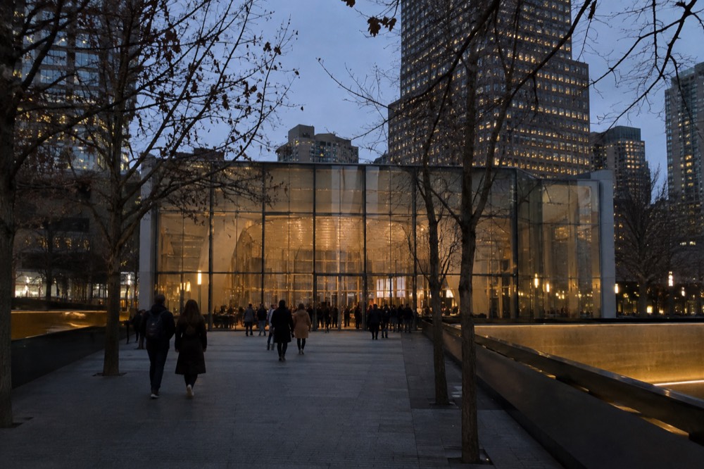 The glass entrance pavilion of the 9/11 Memorial Museum between the two memorial pools