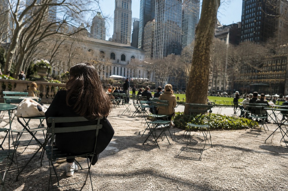 Rows of green movable chairs and tables on the gravel paths of Bryant Park