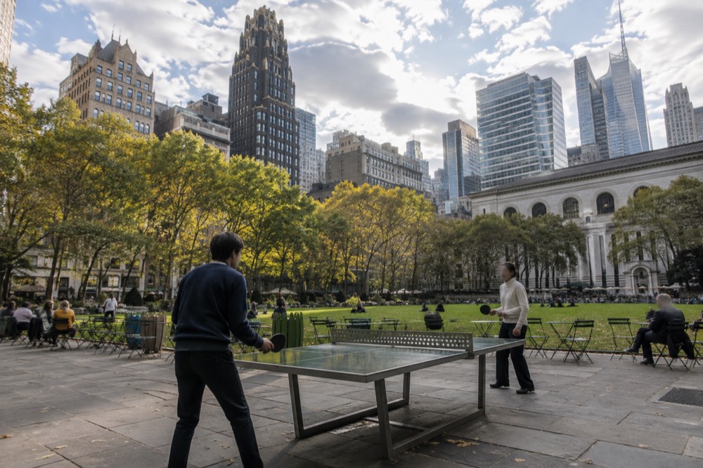 Visitors playing ping-pong at an outdoor table in Bryant Park