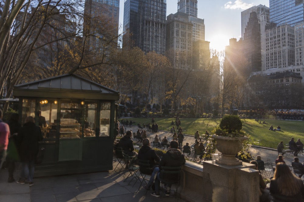 Food kiosk with an awning beside a shaded path in Bryant Park