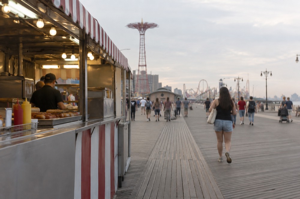 A boardwalk food stand serving hot dogs and drinks to customers