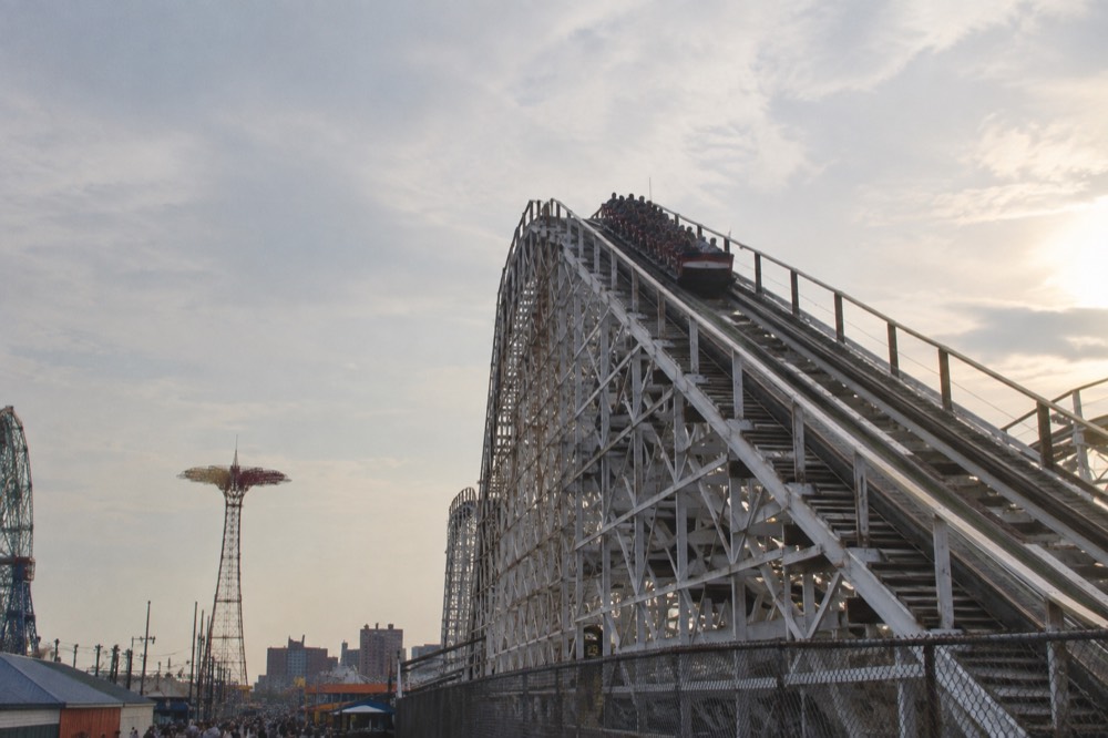 A wooden roller coaster climbing a steep track against the sky