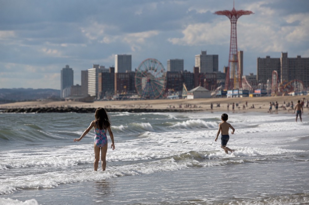 Children playing at the edge of the surf on a wide sandy beach