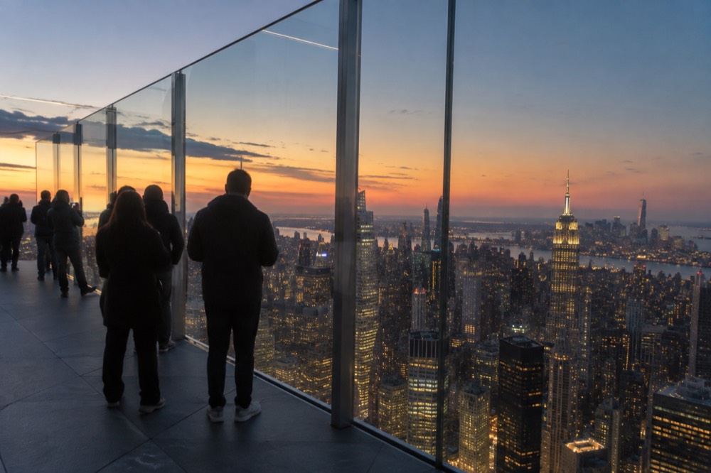 A ticketed observation deck at dusk with the city skyline lit behind glass railings