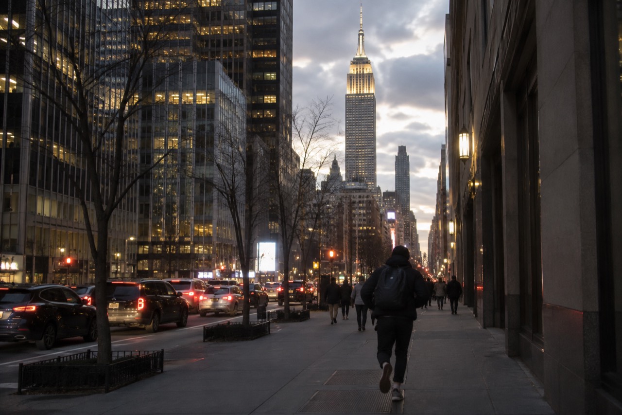 The Empire State Building rising above Midtown Manhattan at dusk, its tower lit against the sky