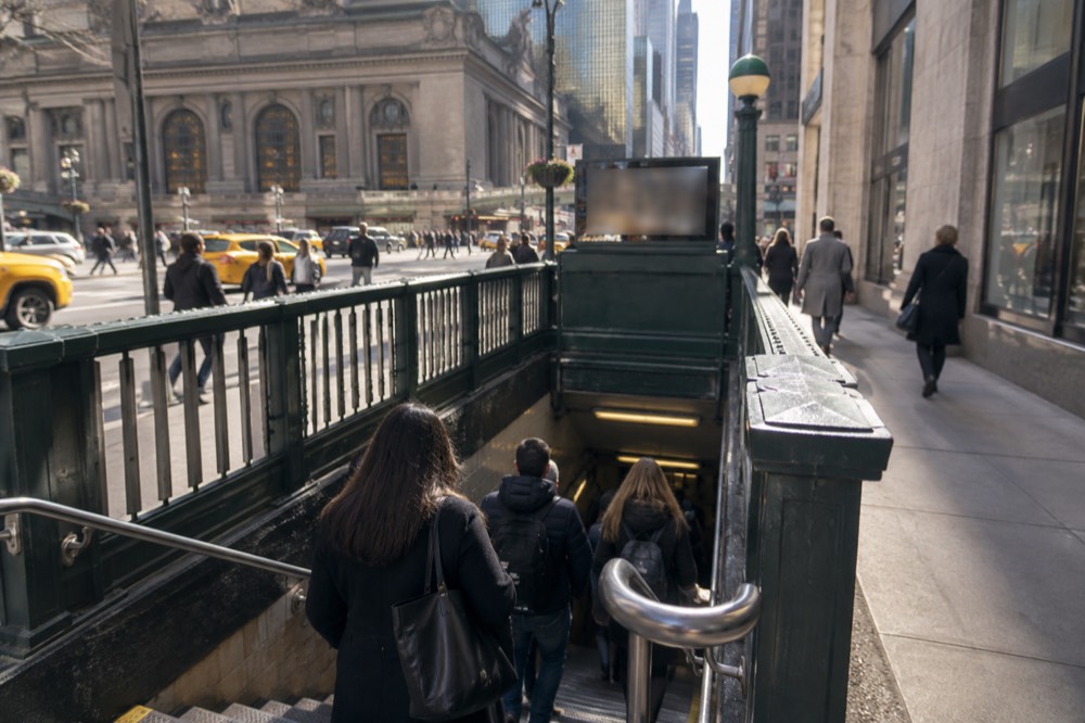 A subway entrance near Grand Central Terminal with passengers descending the stairs
