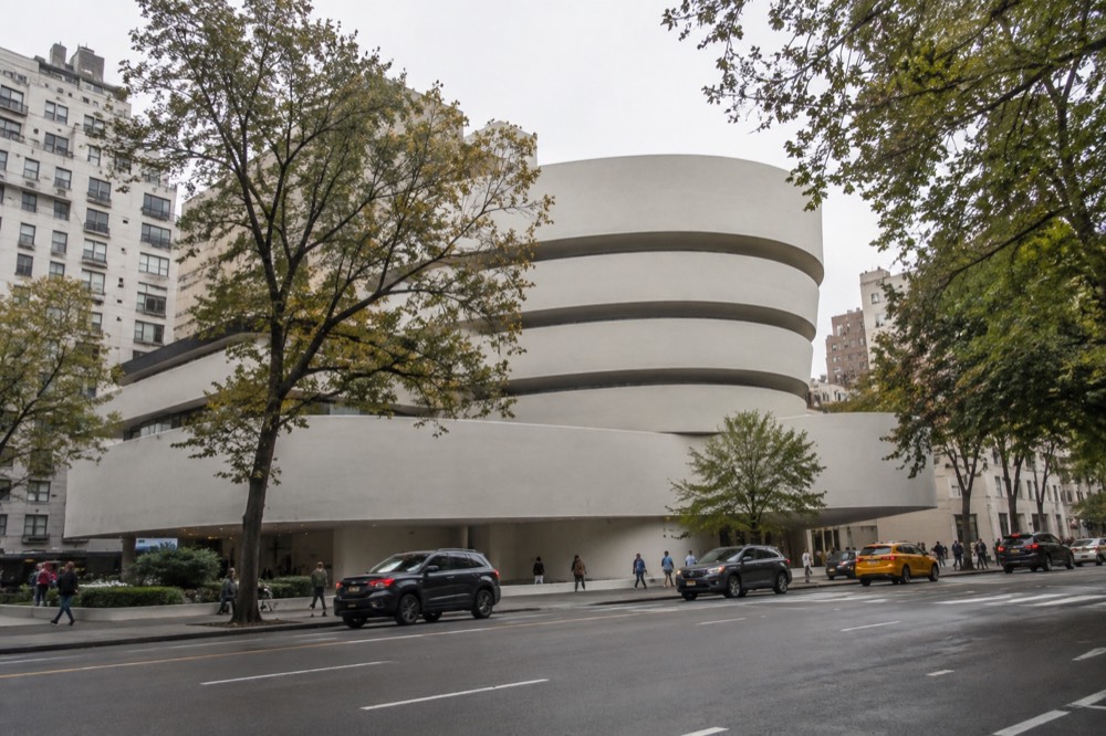 The Guggenheim Museum seen from across Fifth Avenue with trees along the sidewalk