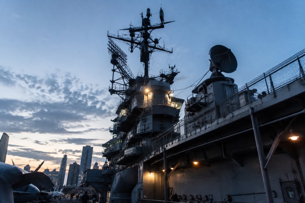 The carrier's island superstructure and radar masts rising above the flight deck in late afternoon light