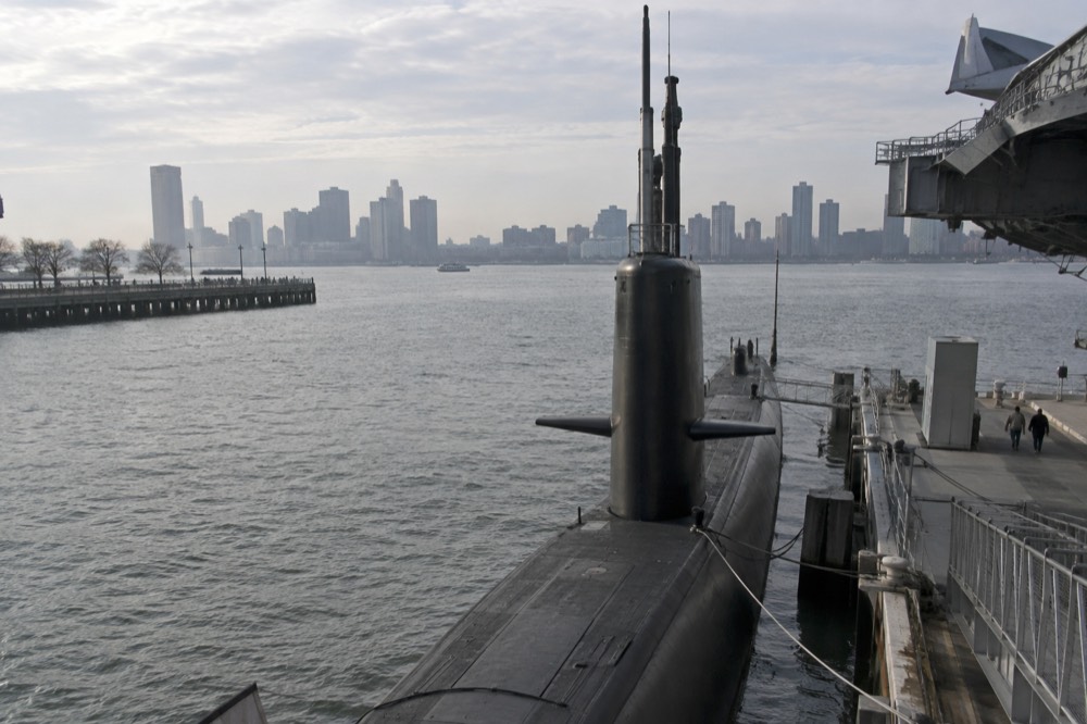 The sail and hull of the submarine Growler moored beside the carrier at the pier