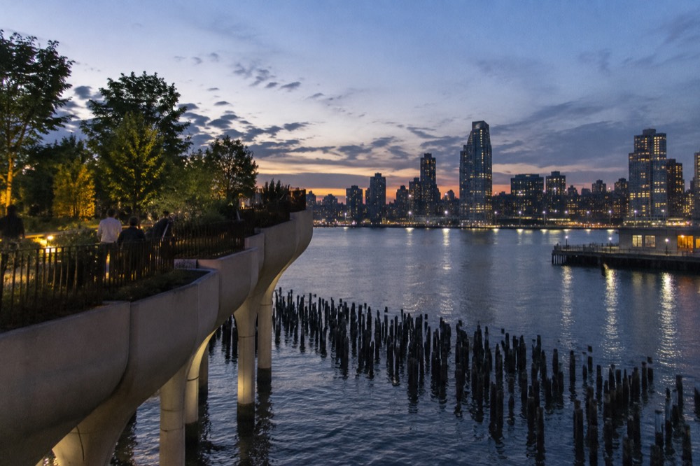 Twilight view from an elevated pier park with city lights reflecting on the Hudson River