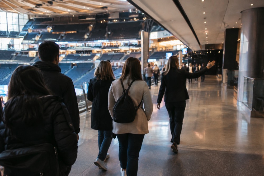 A guide leading a small group of visitors along a concourse inside Madison Square Garden