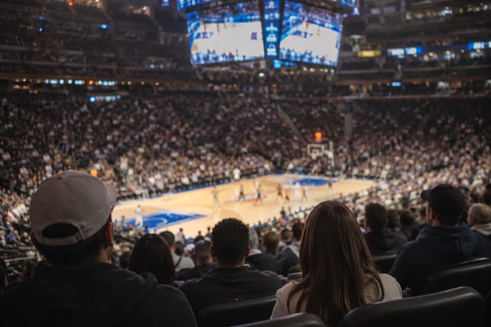 Basketball fans filling the seats at a professional game inside a large indoor arena
