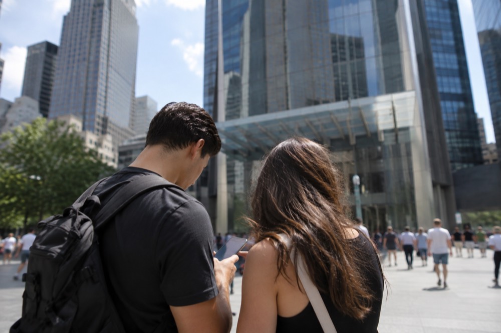 A couple checking their booked time slot on a phone outside One World Trade Center