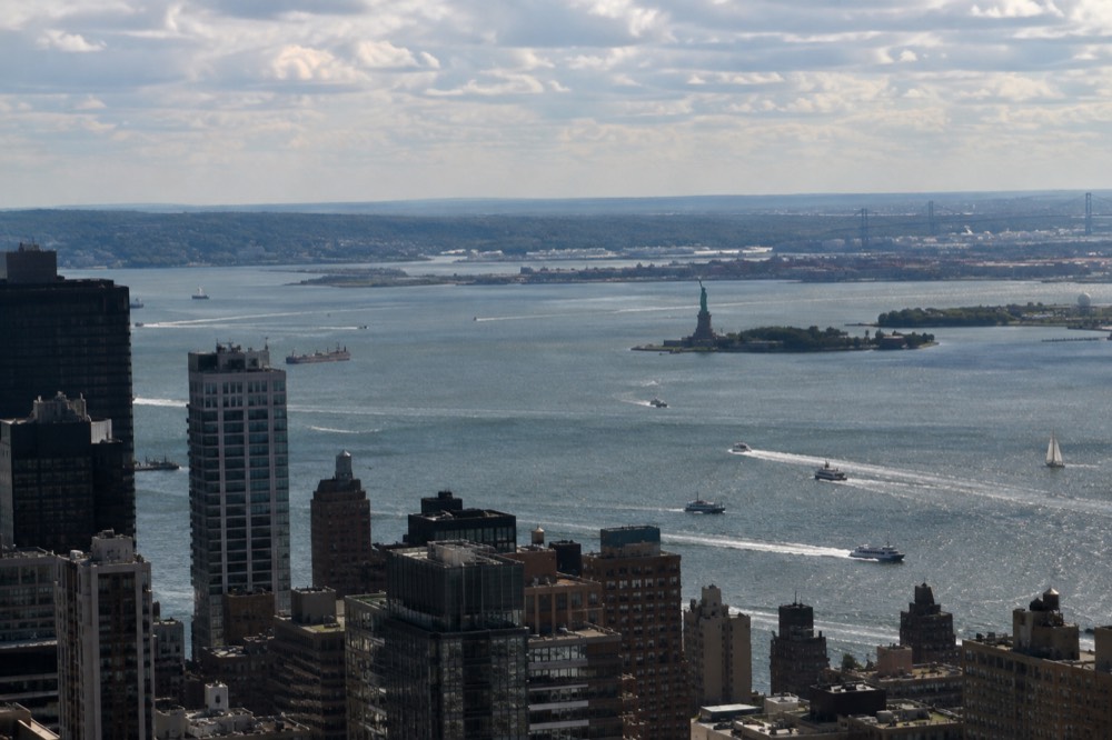 Looking down at the Statue of Liberty and the harbor from high above Lower Manhattan