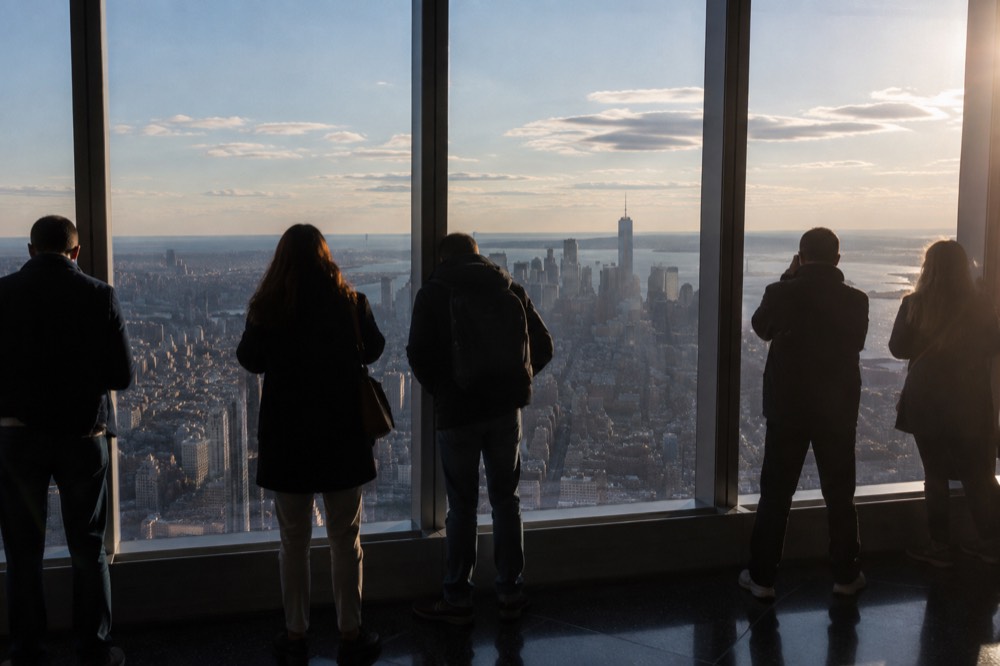 Visitors looking out through the glass walls of an observatory level at the skyline