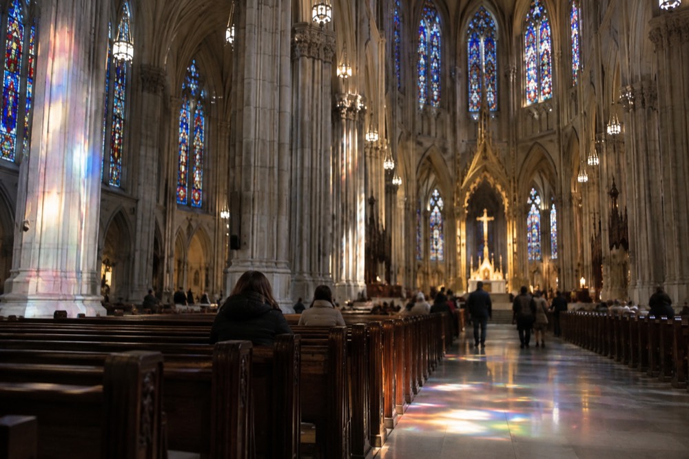 Colored light from stained glass windows falling across the stone floor of the cathedral nave