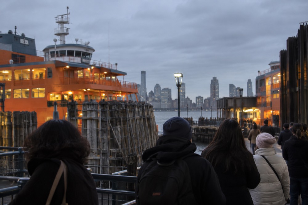 Ferry boats moored at a terminal with passengers waiting on the dock in evening light