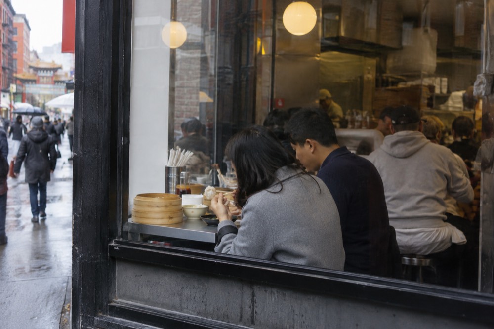 People eating dumplings at a small counter restaurant in Chinatown