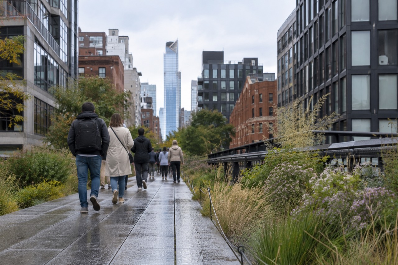 Visitors strolling along the High Line's planted walkway with Manhattan buildings rising on both sides
