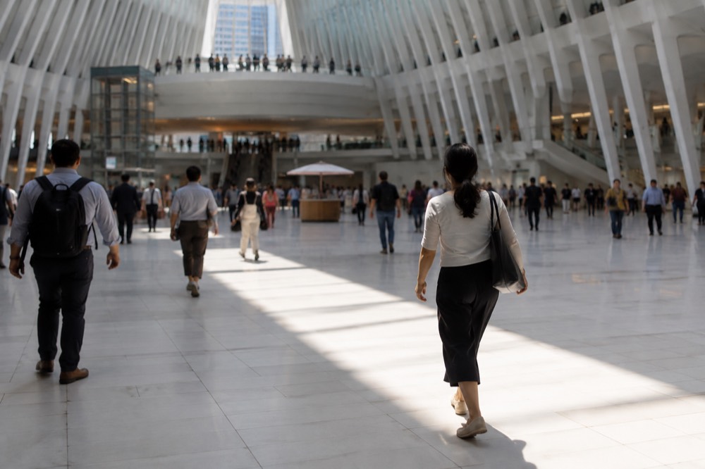 A commuter walking across the white marble floor of the Oculus main hall