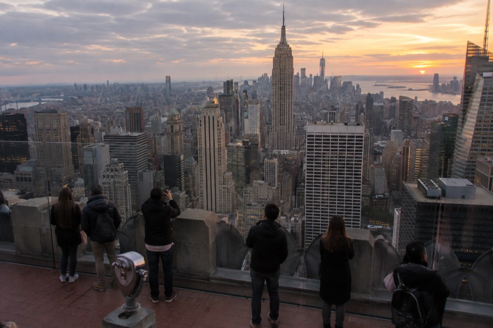 The Top of the Rock observation deck at golden hour with the Manhattan skyline behind the railings