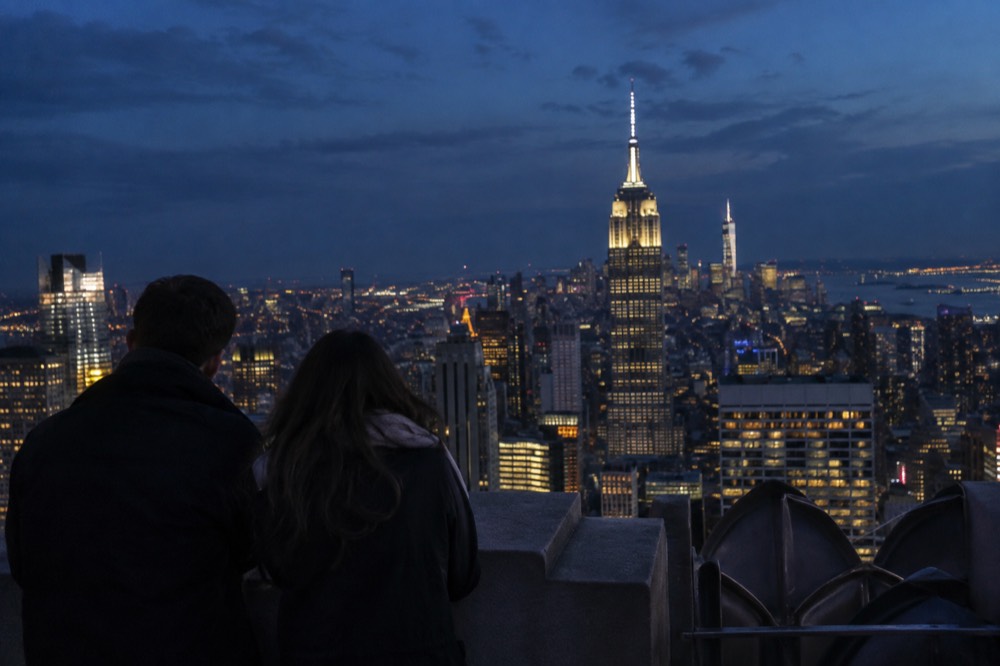 A couple viewing the illuminated Manhattan skyline at night from the Top of the Rock deck