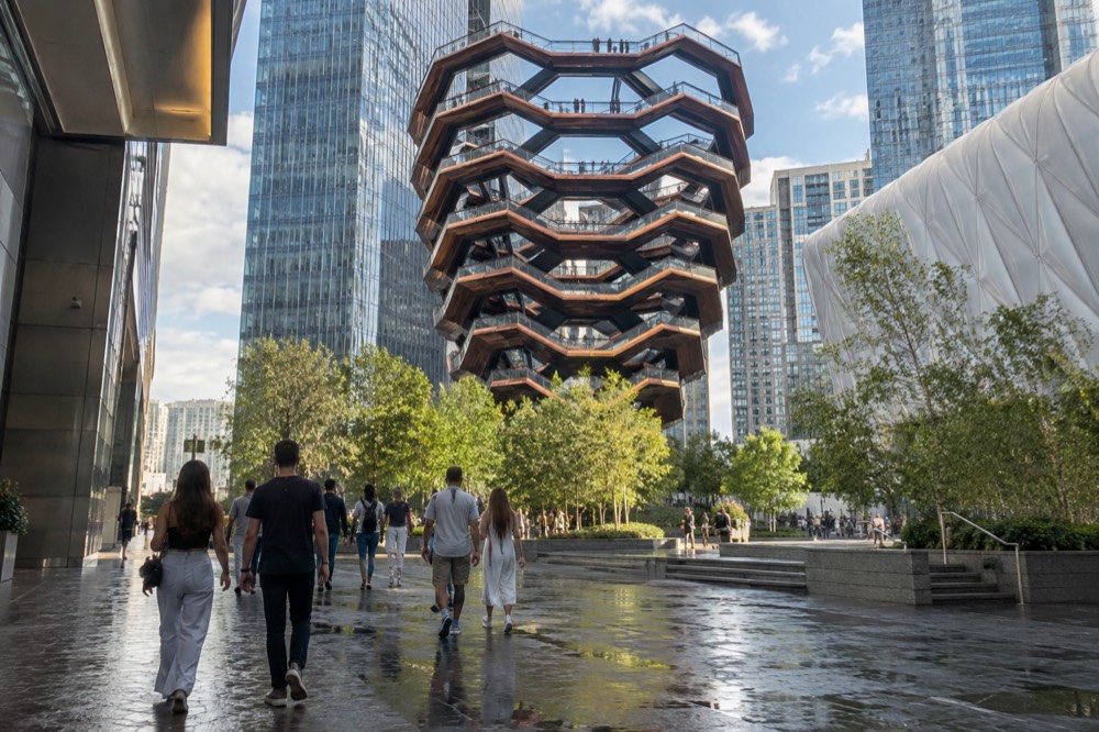 Visitors walking across the Hudson Yards plaza toward Vessel on a sunny afternoon