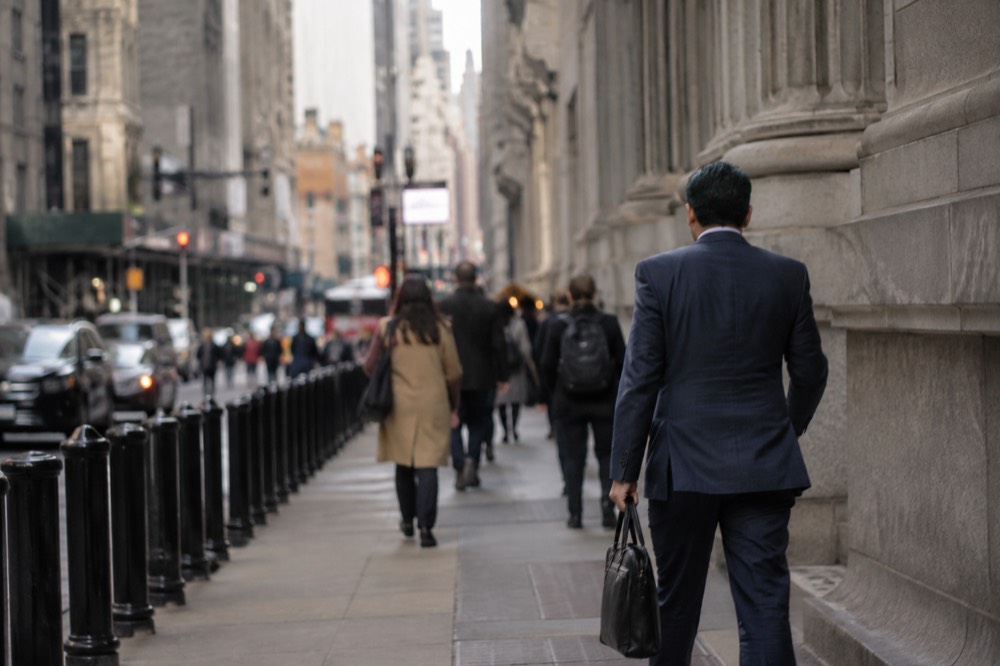 Morning sunlight along the narrow Wall Street canyon with office workers walking