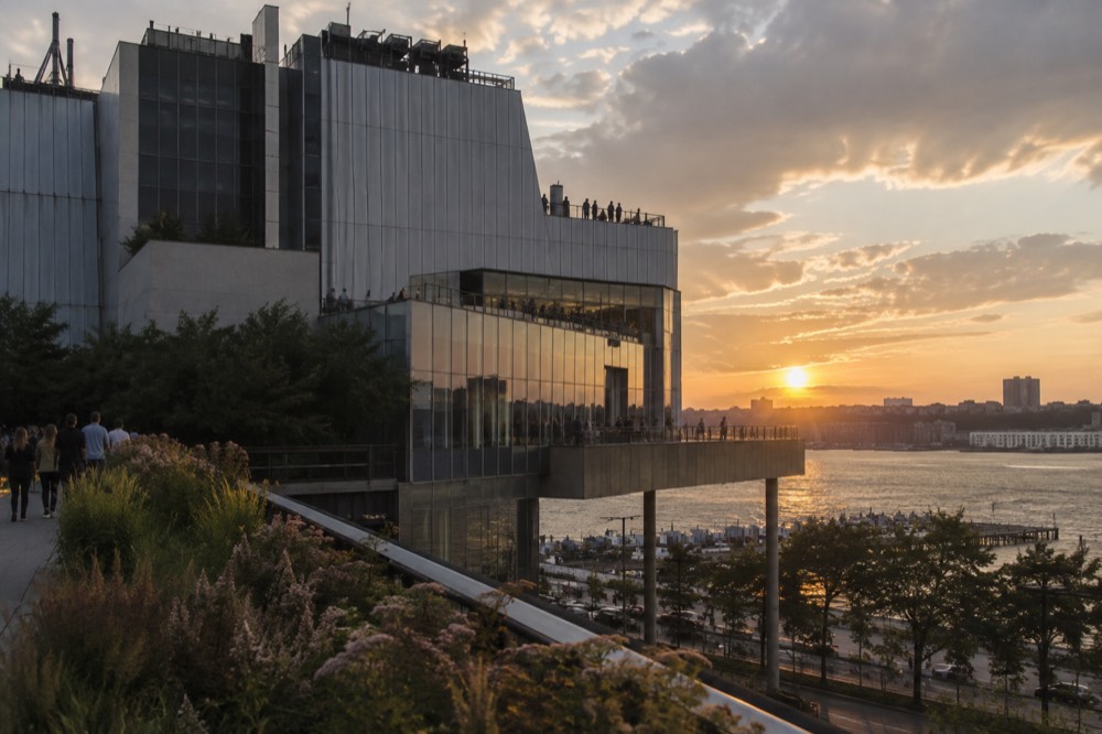 The Whitney Museum building rising above the High Line at sunset, with gallery terraces overlooking the Hudson River