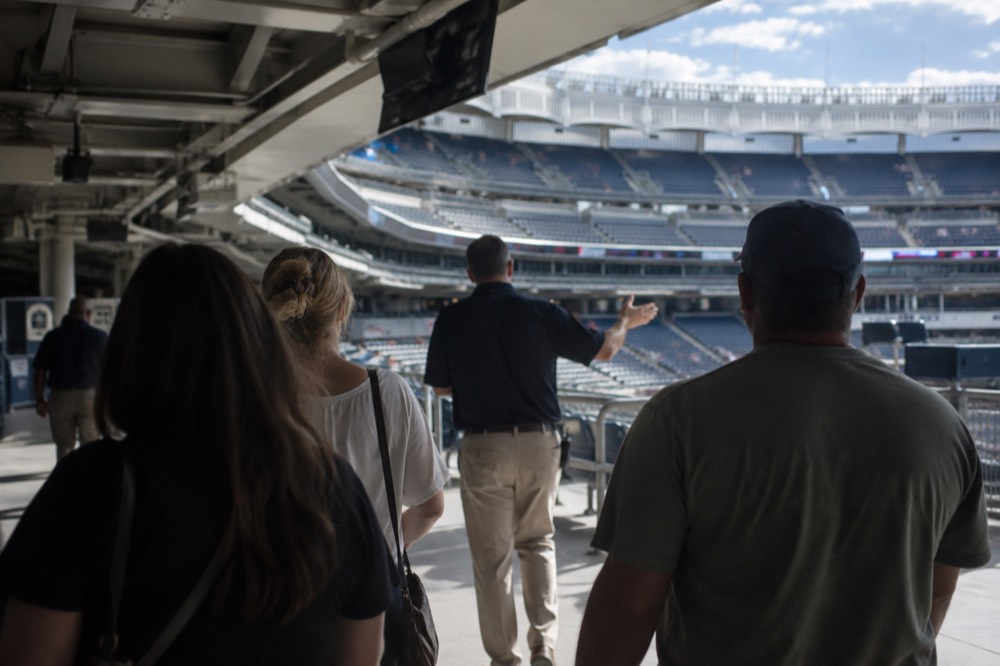 A guide leading a small group of visitors along the seating concourse inside Yankee Stadium