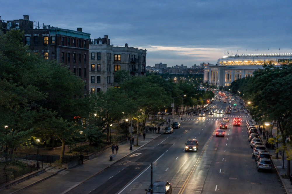 A wide boulevard in the Bronx lined with apartment buildings and shops near the stadium