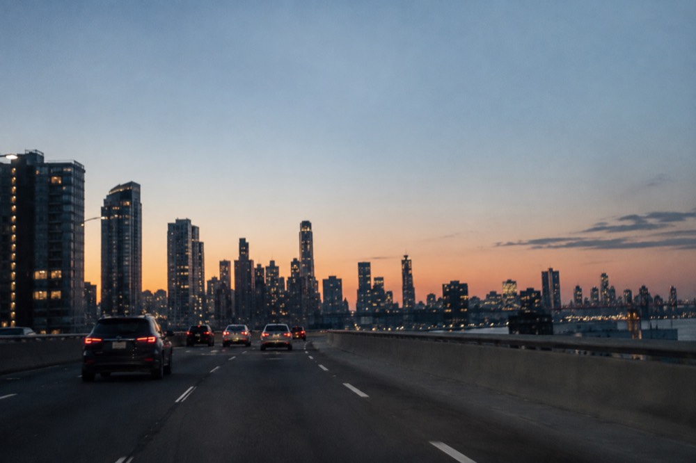 A highway heading out of the city with light morning traffic under a clear sky