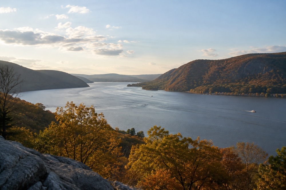 A wide view of the Hudson River between golden hills in late afternoon light