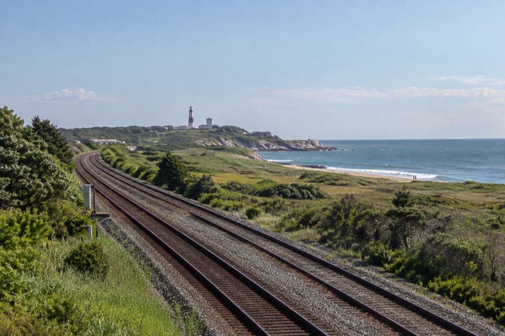 A double-track railroad running past green fields toward the eastern Long Island shore