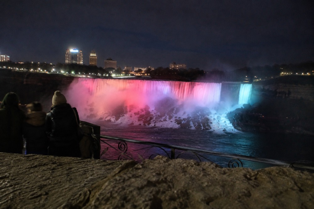 Falls illuminated at night with colored lights playing on the water