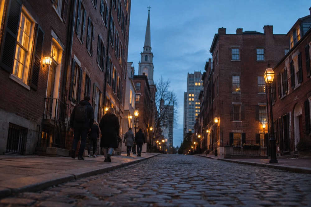 People walking along a cobblestone street lined with old brick buildings in Philadelphia's historic district