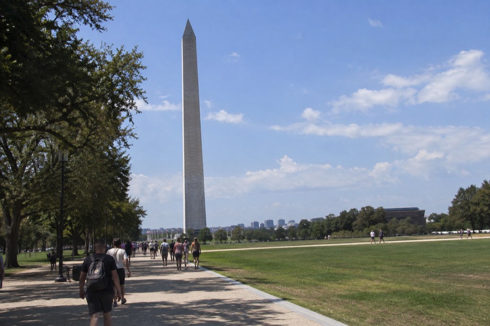 The Washington Monument rising above the National Mall with visitors walking along the paths