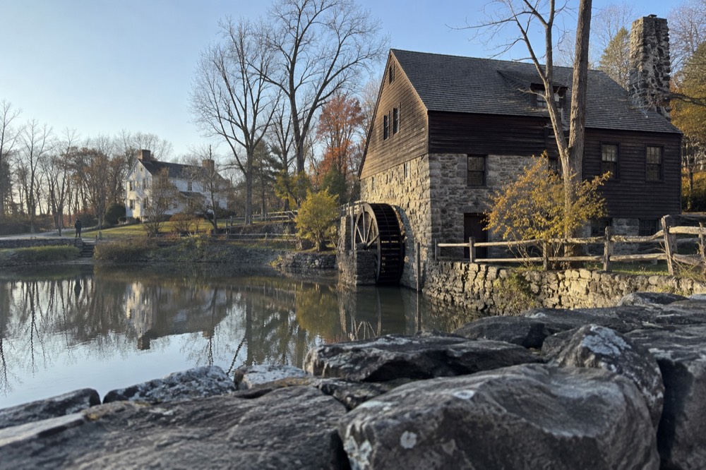 Colonial-era manor house with a water mill beside a mill pond