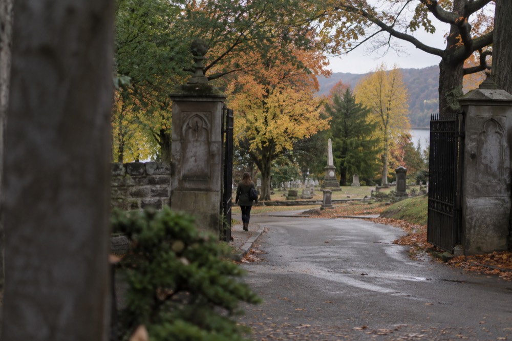 Stone gates and a winding lane at the entrance to a historic cemetery in autumn
