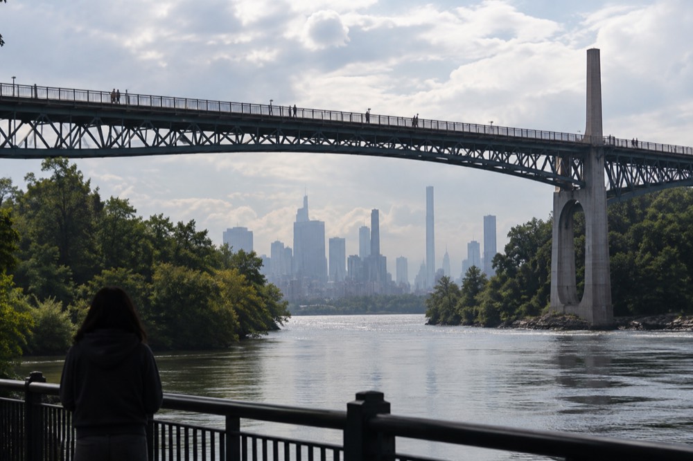A long elevated pedestrian bridge spanning a wide river between wooded banks