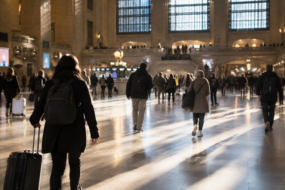 Interior of a busy train station concourse with travelers carrying bags