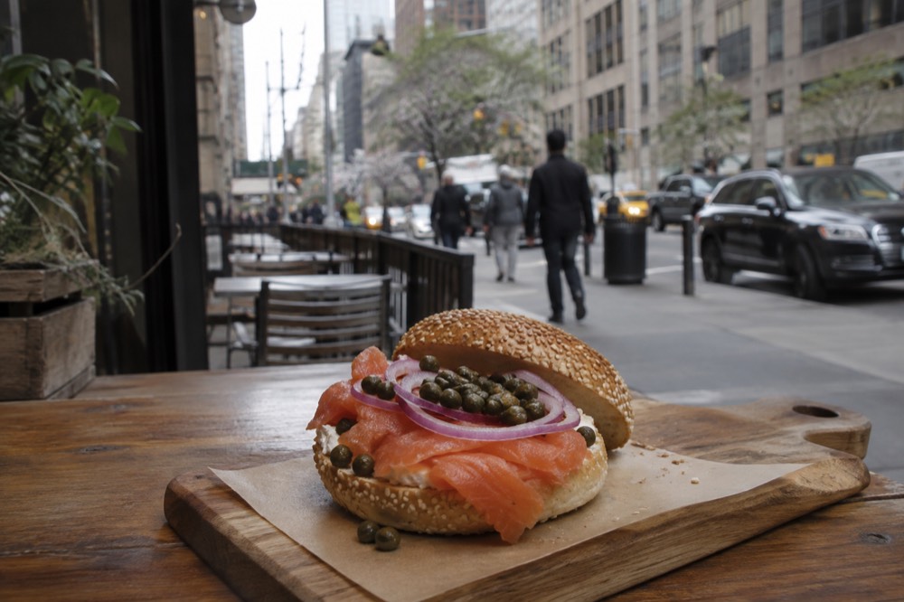 A bagel with smoked salmon, capers and onion on a wooden board