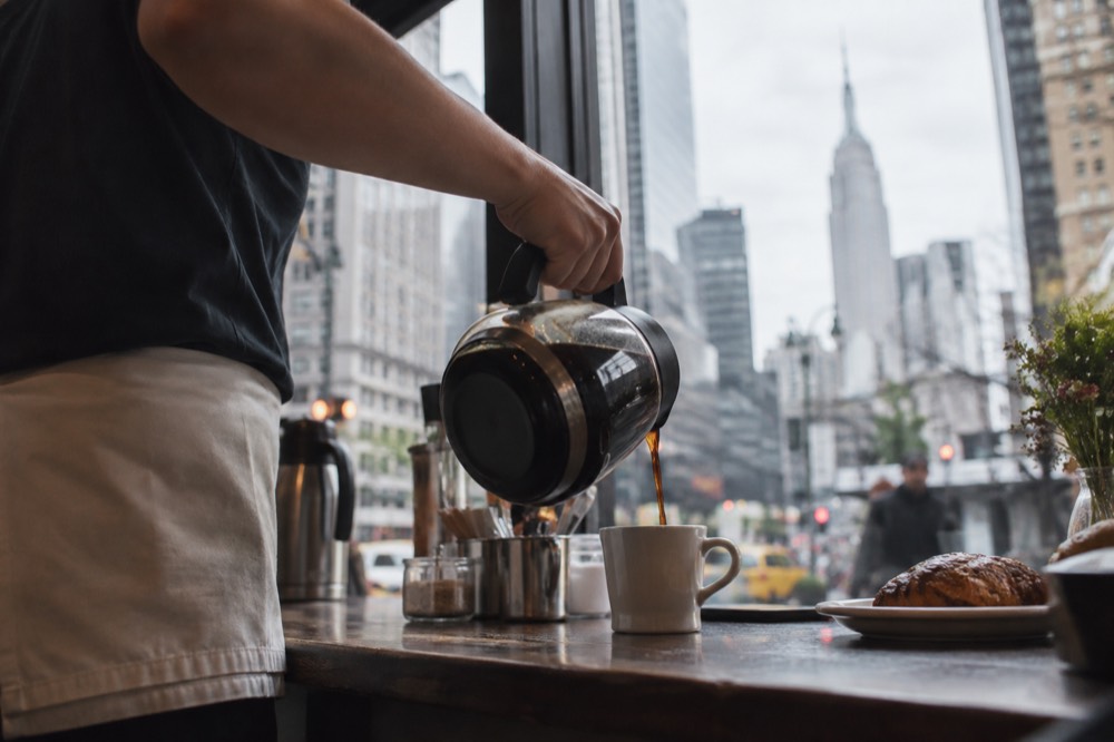 Coffee being poured at a New York brunch counter in morning light