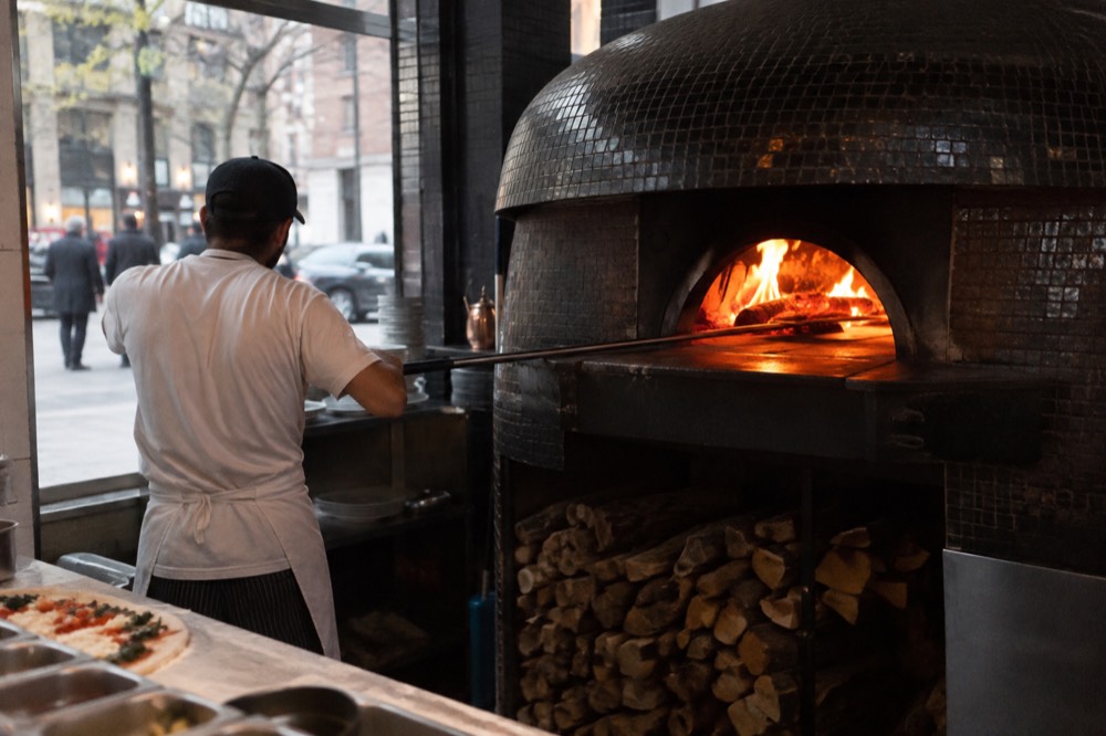 A wood-fired oven glowing inside a Neapolitan pizzeria in New York