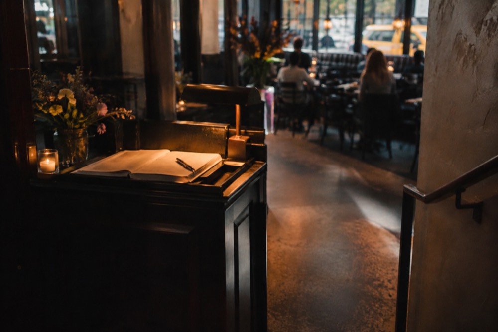 A host stand with a reservation book inside a dimly lit New York restaurant