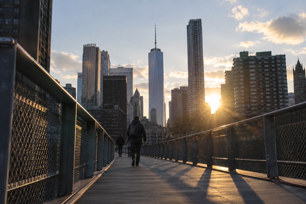 A quiet pedestrian bridge walkway at sunrise with the skyline ahead