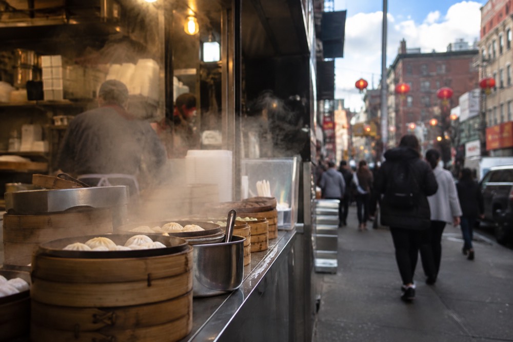 Steam rising from dumpling baskets at a Chinatown counter
