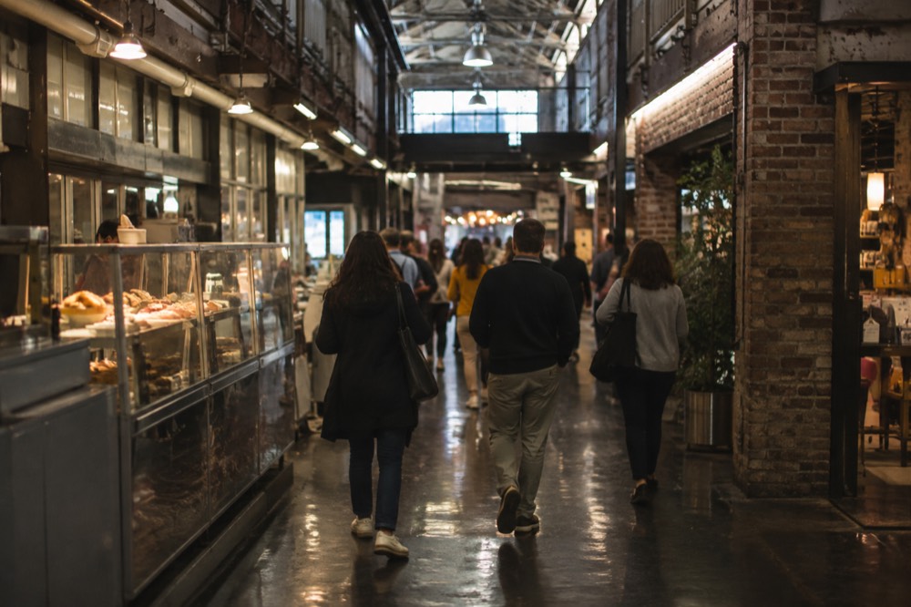 Food stalls and shoppers inside Chelsea Market's brick corridor